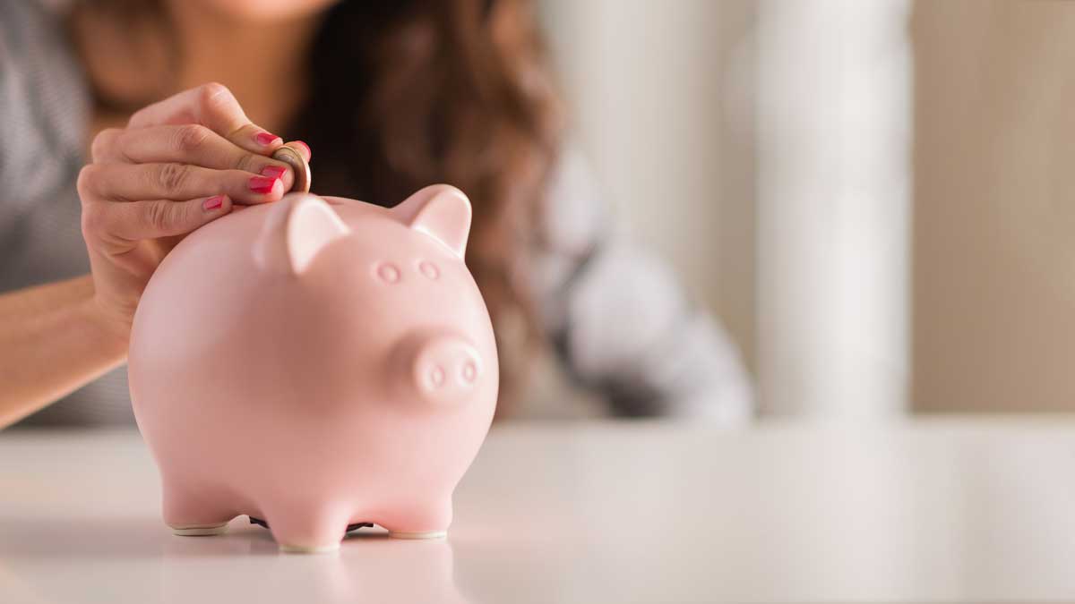 Woman putting money in piggy bank